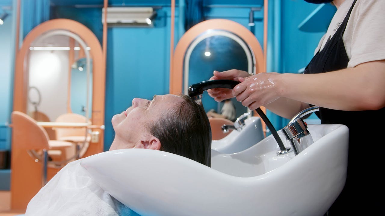 A senior woman gets a relaxing hair wash at a vibrant, modern salon setting.