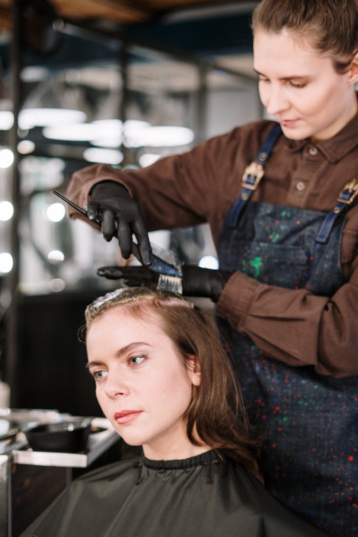 A hairstylist expertly dyes a womans hair in a contemporary salon setting, highlighting beauty and care.