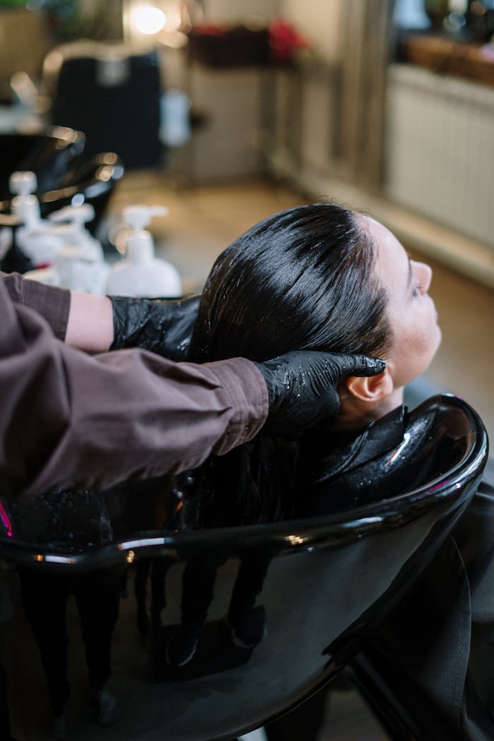 A professional hairstylist washing a womans hair in a modern salon setting, ensuring quality haircare.